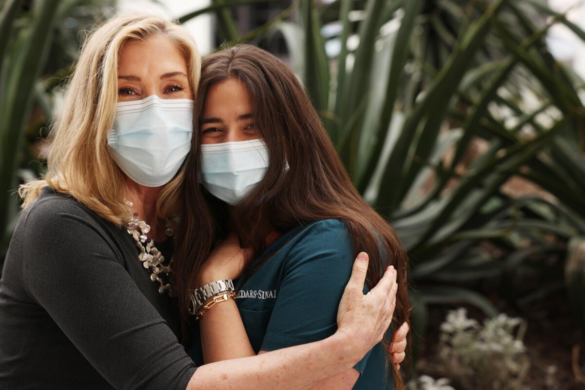 Two women in masks hug