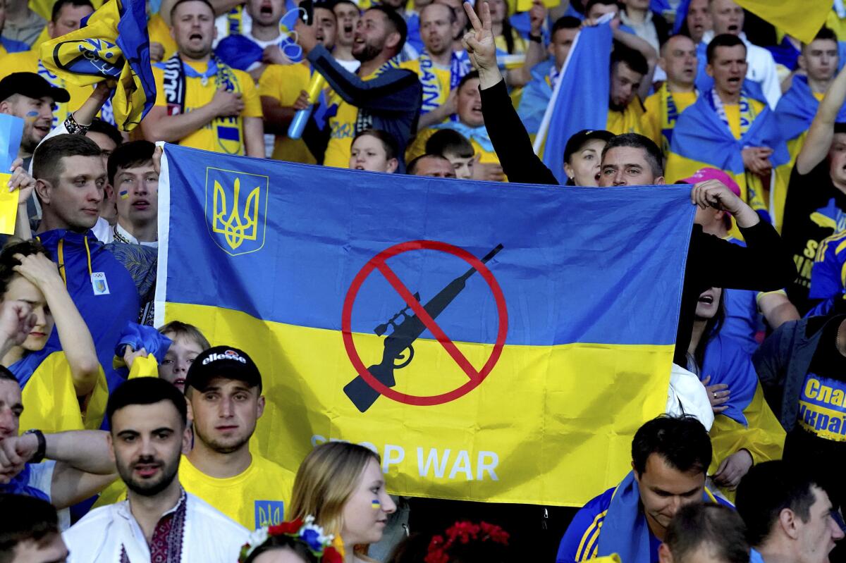 Ukraine fans hold up an anti-war banner at the end of the World Cup 2022 qualifying play-off soccer match between Scotland and Ukraine at Hampden Park stadium in Glasgow, Scotland, Wednesday, June 1, 2022. (Andrew Milligan/PA via AP)