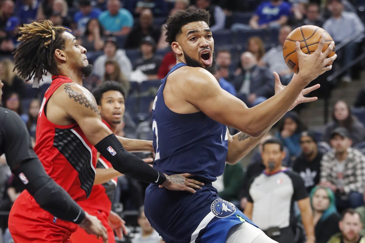 Minnesota Timberwolves center Karl-Anthony Towns, right, goes to the basket around Portland Trail Blazers forward Greg Brown III in the first quarter of an NBA basketball game Monday, March 7, 2022, in Minneapolis. (AP Photo/Bruce Kluckhohn)