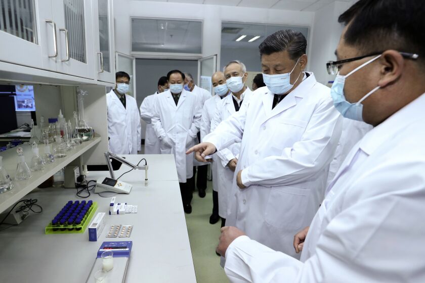 In this photo released by Xinhua News Agency, Chinese President Xi Jinping, second right, wearing a protective face mask, talks to a medical staff members during his visit to the Academy of Military Medical Sciences in Beijing, Monday, March 2, 2020. The number of new virus infections rose worldwide along with fears of a weakening global economy, even as cases in China dropped to their lowest level in six weeks on Monday and hundreds of patients at the outbreak's epicenter were released from hospitals. (Ju Peng/Xinhua via AP)