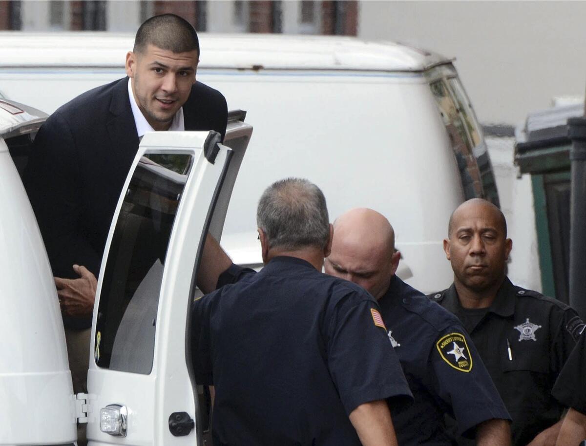Former New England Patriots star Aaron Hernandez is escorted out of a van as he arrives for a hearing.