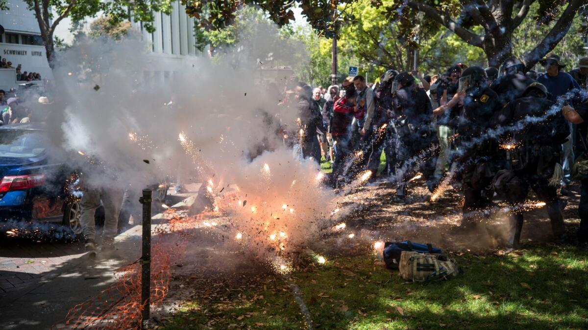 A firework thrown by someone in the crowd explodes at the feet of police and supporters of President Trump as they clash with protesters at an April 15 rally in Berkeley organized by the Trump supporters.