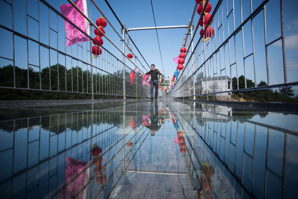 A tourist walks across the glass bridge in Shiniuzhai National Geological Park in central China before one of its panel's shattered.