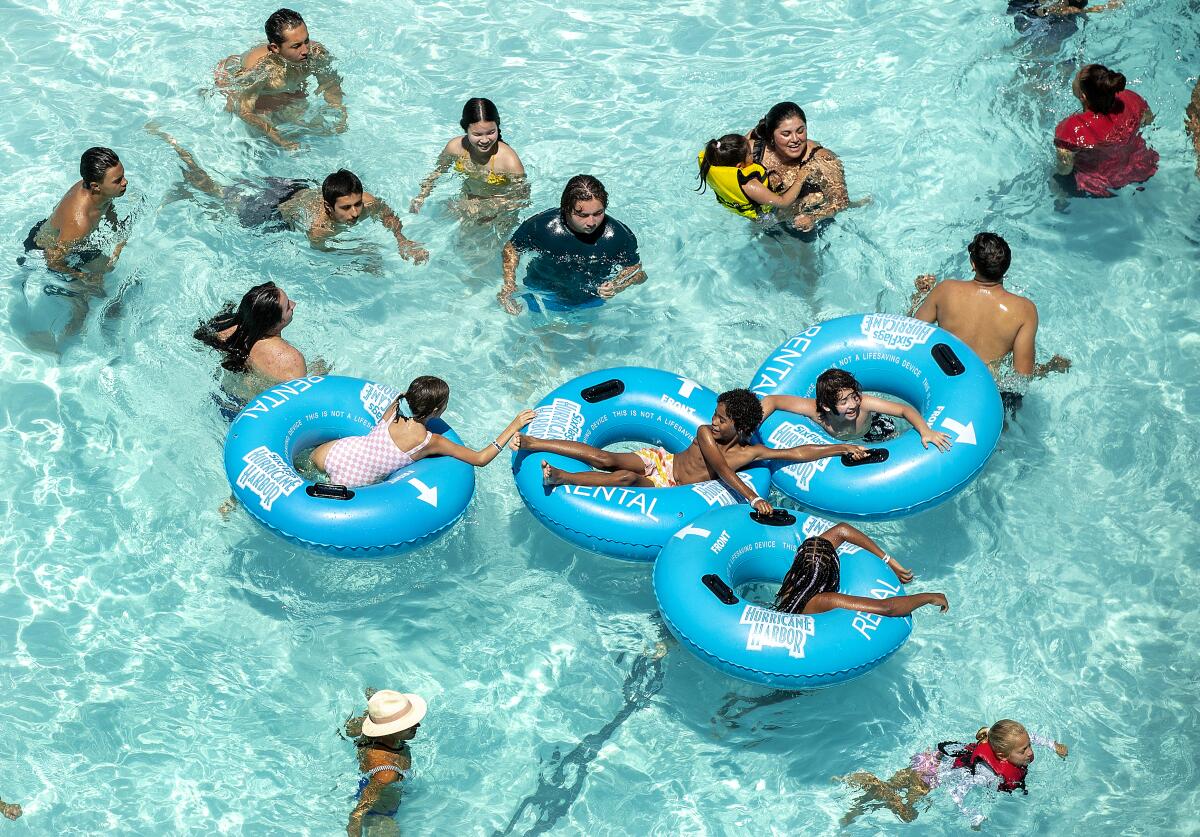 Children float in inner tubes as other people wade in a pool