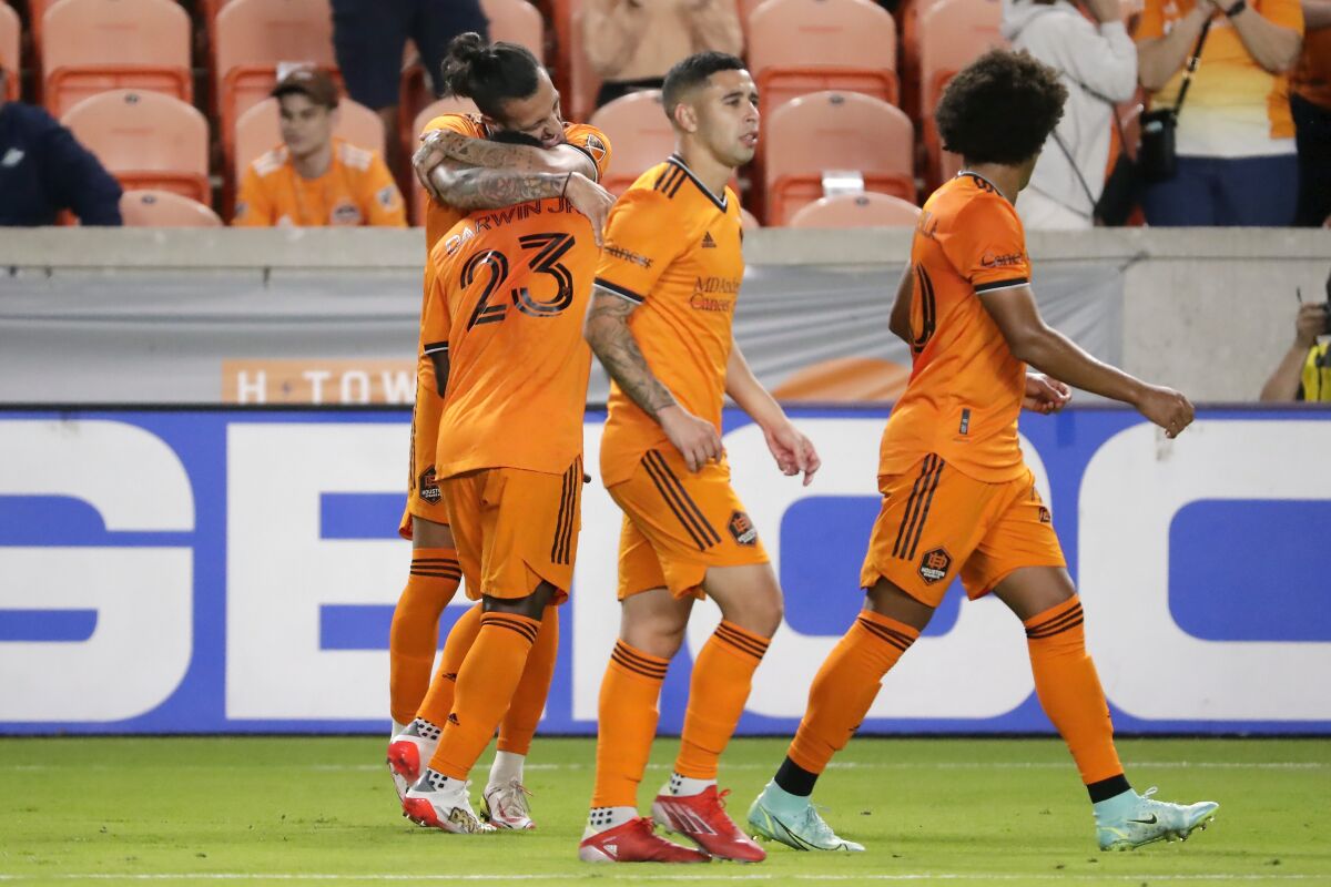 Houston Dynamo's Maximiliano Urruti hugs Carlos Darwin Quintero (23) as they celebrate Urruti's goal as Matias Vera, center, and Adalberto Carrasquilla, right, walk away during the first half of an MLS soccer match against the Seattle Sounders, Saturday, Oct. 16, 2021, in Houston. (AP Photo/Michael Wyke)