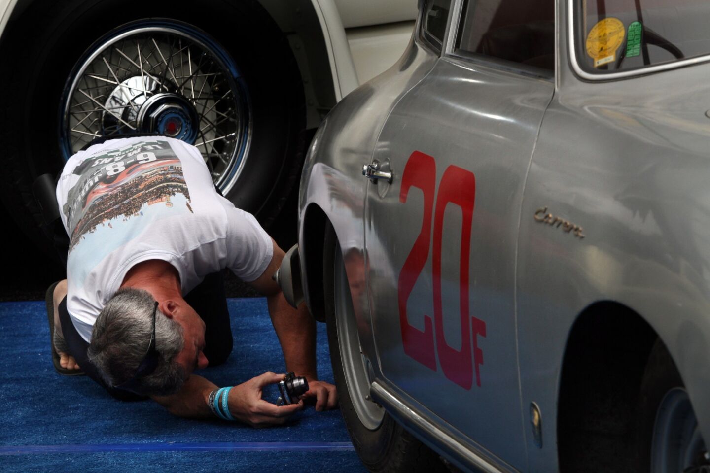 A man uses a camera to get a closer look at the undercarriage of a 1956 Porsche 356 A 1500 GS Carrera Coupe.
