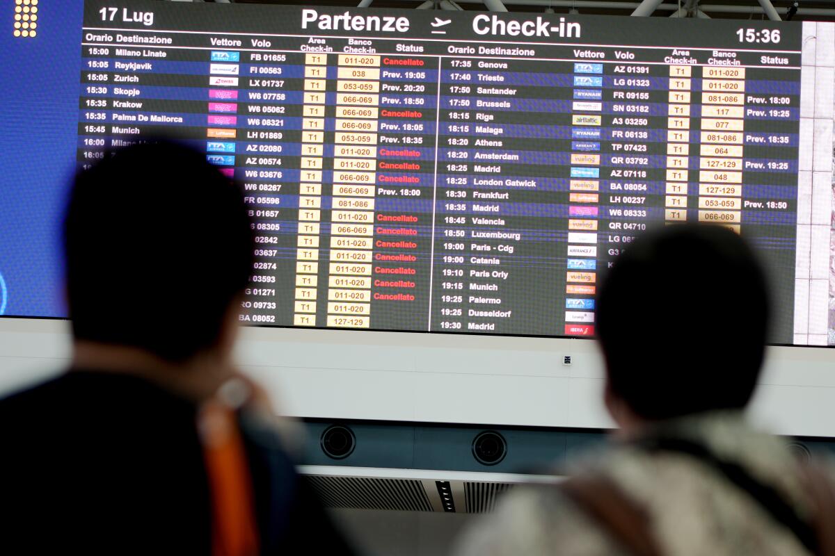 Passengers look at flights timetables in Rome's Leonardo Da Vinci international airport, Sunday, July 17, 2022. Several hundred flights were canceled in Italy Sunday, a peak vacation travel day, because of four-hour walkouts involving employees of low-cost airlines as well as air traffic controllers. (AP Photo/Andrew Medichini)