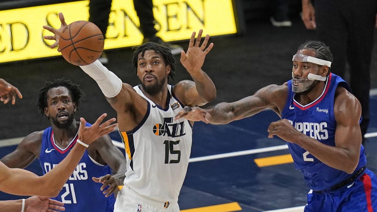 Utah Jazz center Derrick Favors reaches for the ball between Clippers guard Patrick Beverley and forward Kawhi Leonard.