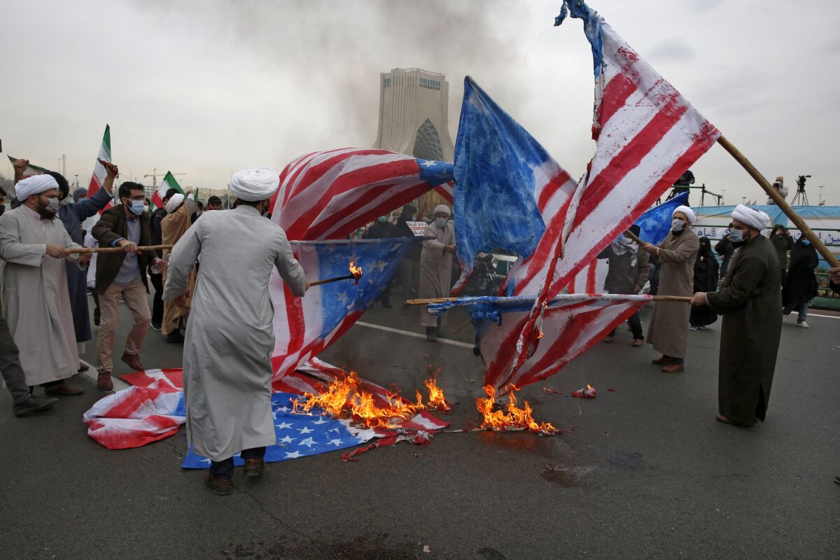 Clerics burn representations of the U.S. flag during the annual rally commemorating anniversary of Iran's 1979 Islamic Revolution at the Azadi (freedom) square in Tehran, Iran, Friday, Feb. 11, 2022. Thousands of cars and motorbikes paraded in the celebration, although fewer pedestrians were out for a second straight year due to concerns over the coronavirus pandemic. (AP Photo/Vahid Salemi)