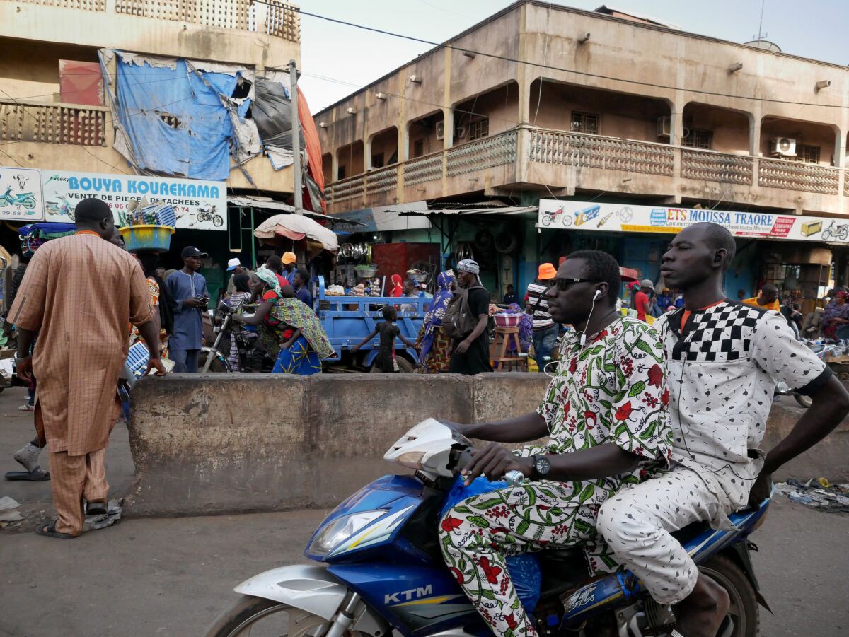 Men ride a motorbike past the Dabanani market in Bamako, Mali. Despite rapid gains in internet penetration in West Africa, most Malians, who cannot read or write, still find the web of limited use.