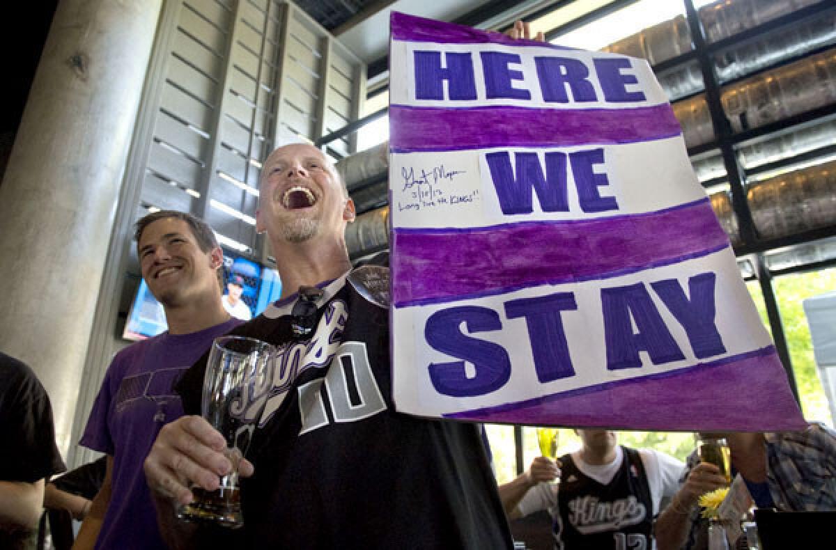 Kings fan Kris Haskins holds a "Here We Stay" sign after hearing the NBA owners rejected the franchise's move to Seattle on Wednesday.