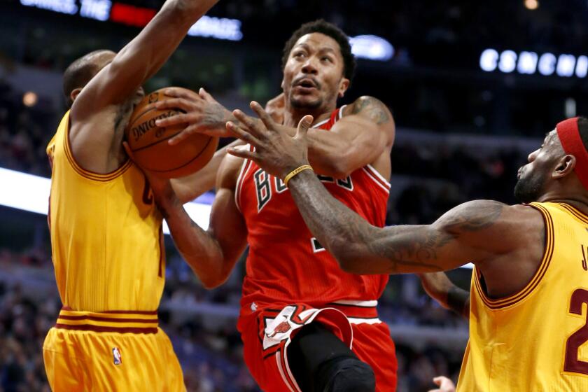 Bulls point guard Derrick Rose (1) scores despite the double-team defense of Cavaliers forwards James Jones, left, and LeBron James in the second half Thursday night in Chicago.