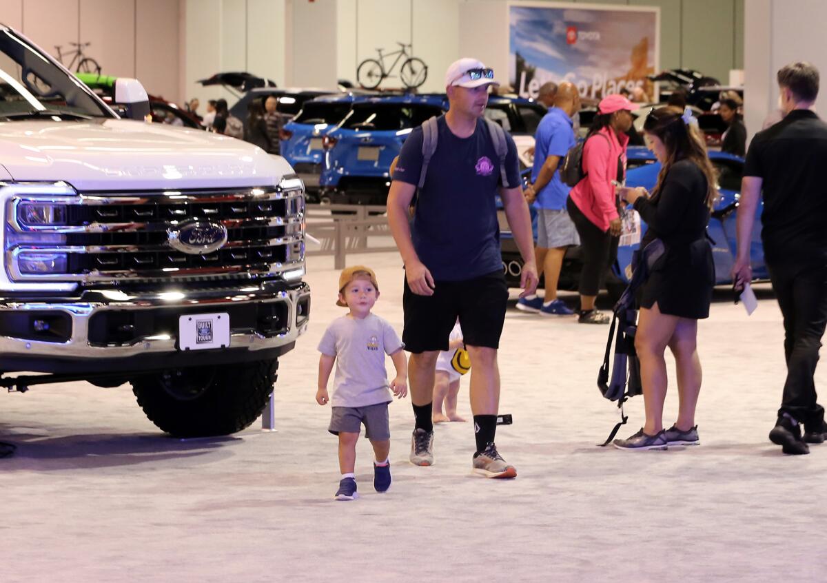 Families walk through the Anaheim Convention Center looking at new model cars.