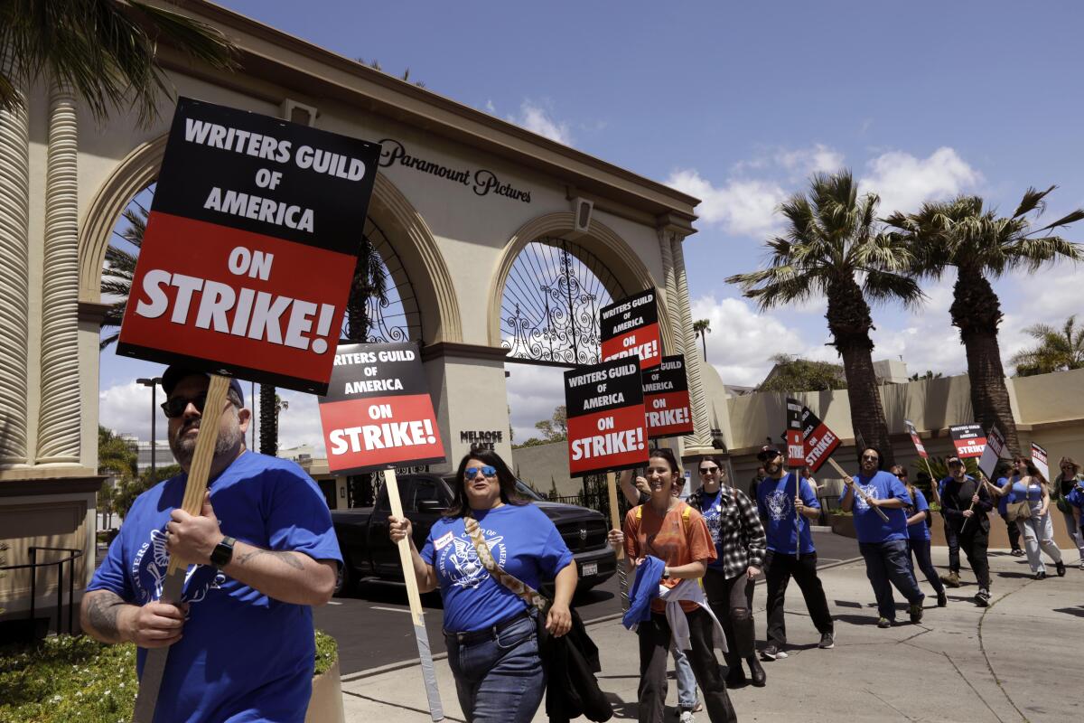 WGA members walk the picket line with signs in front of Paramount Studios.