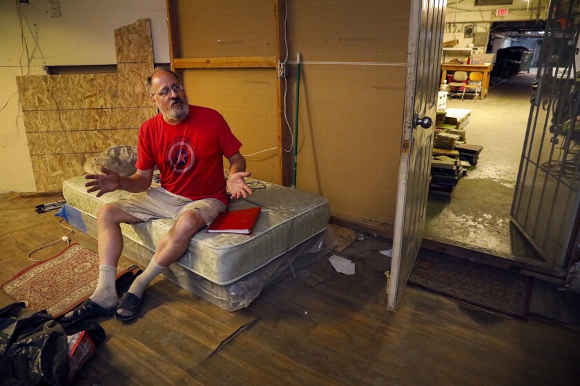 Mark Miner sits on the bed of his basement apartment below the C Street Inn.