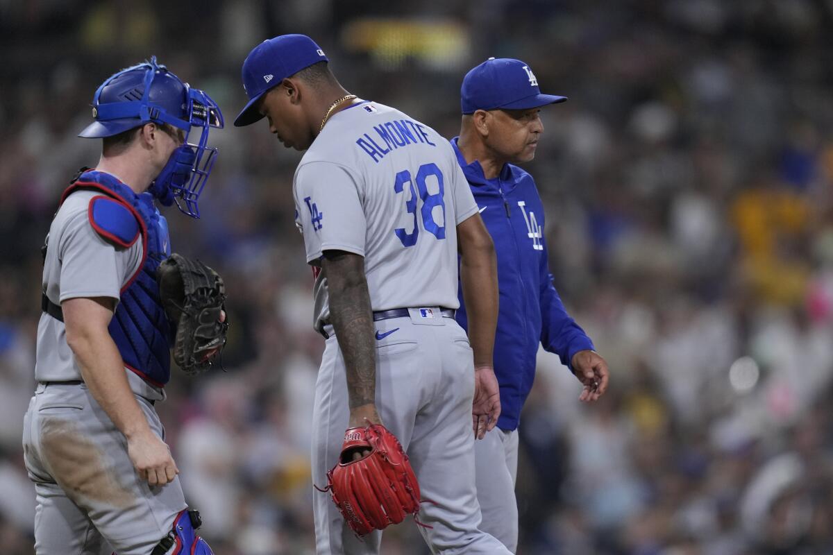 Los Angeles Dodgers manager Dave Roberts takes the ball from relief pitcher Yency Almonte in front of Will Smith.
