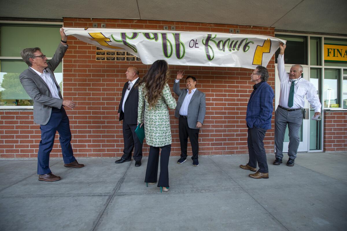 Kelly Gallagher, left, and Bruce Belcher, right, unveil the newest plaques to Edison High School's Hall of Fame.  