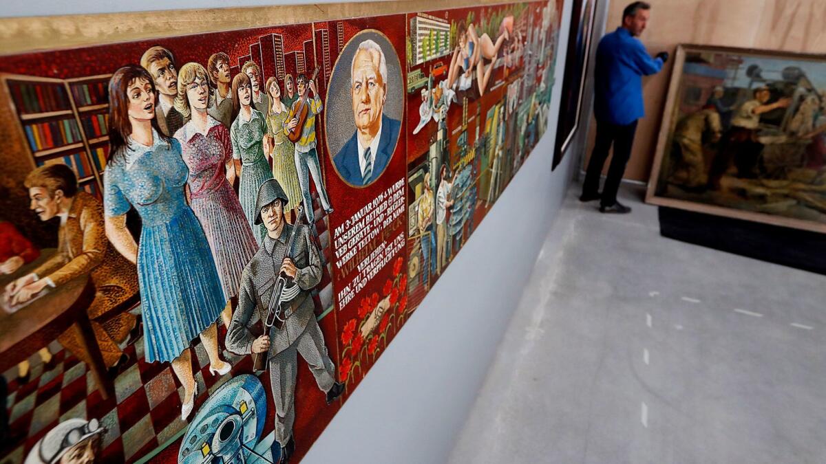 Joes Segal, chief curator of the Wende Museum, helps to install artwork in the museum's new home in a former National Guard armory building in Culver City.