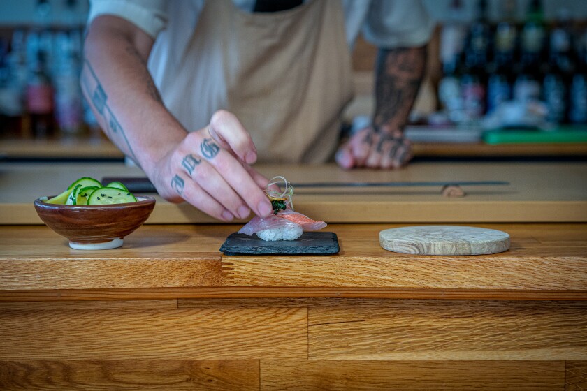 A sushi chef serves a portion of nigiri at Sushi by Scratch Restaurant.