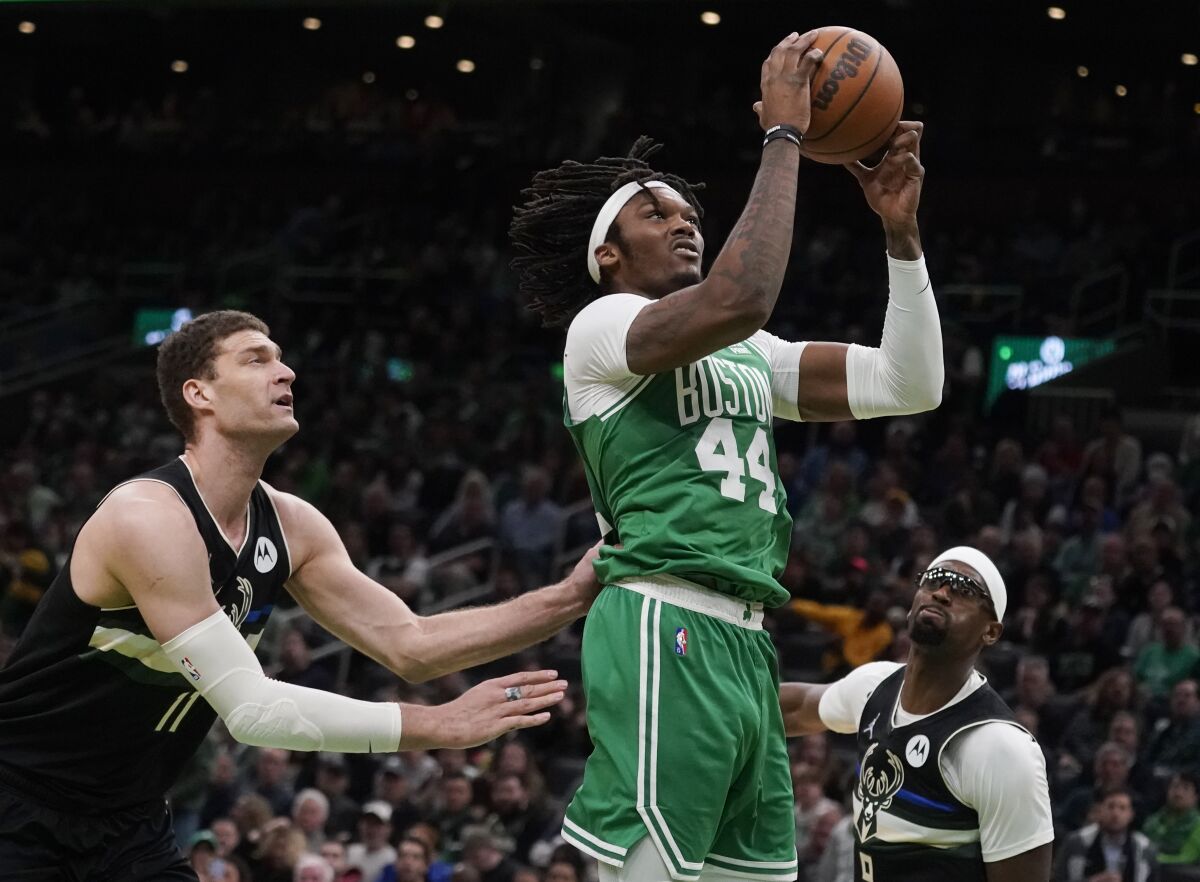 Boston Celtics center Robert Williams III (44) drives to the basket against Milwaukee Bucks center Brook Lopez (11) and center Bobby Portis, right, during the second half of Game 2 of an Eastern Conference semifinal in the NBA basketball playoffsTuesday, May 3, 2022, in Boston. (AP Photo/Charles Krupa)