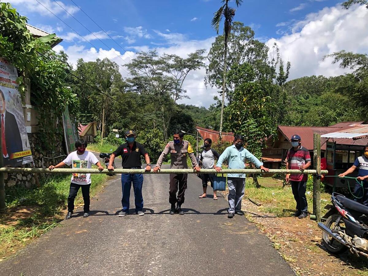 People from the Buntao community in Indonesia use a wooden barrier to block off their village. Indigenous peoples across the archipelago are locking down their villages in an effort to protect against the coronavirus.