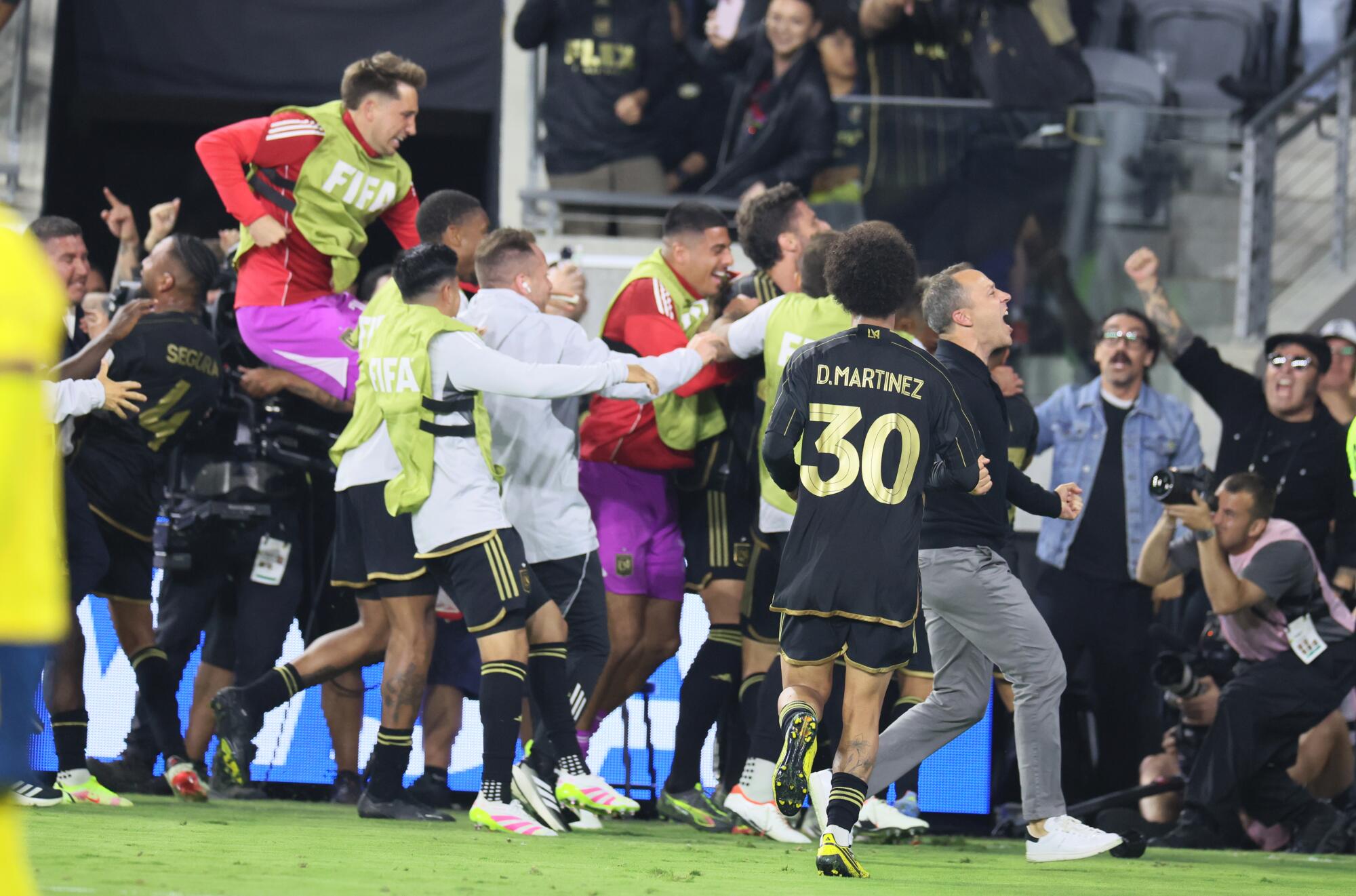 LAFC coach Steve Cherundolo and players run to the corner of the pitch to celebrate.