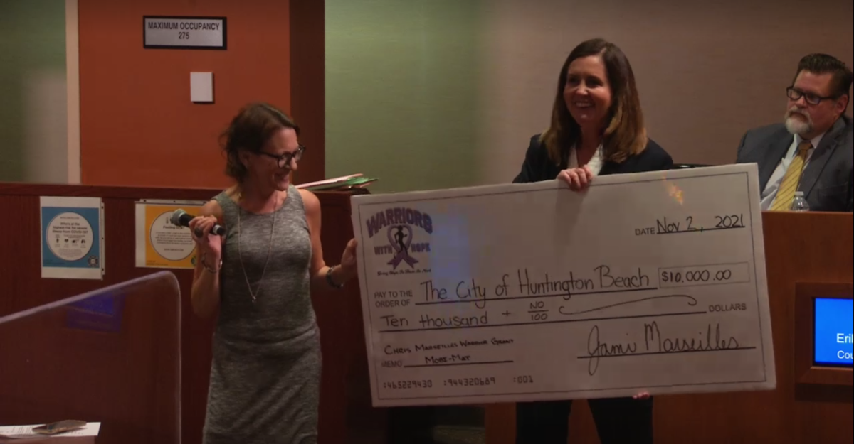 Jami Marseilles, left, presents Mayor Kim Carr with a $10,000 check during the City Council meeting on Nov. 2, 2020.