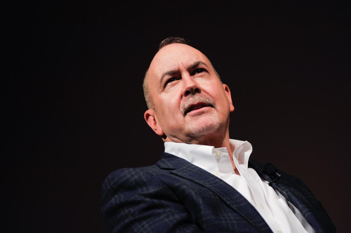 Terence Winter, in a white collared shirt and blazer, looks into the audience.