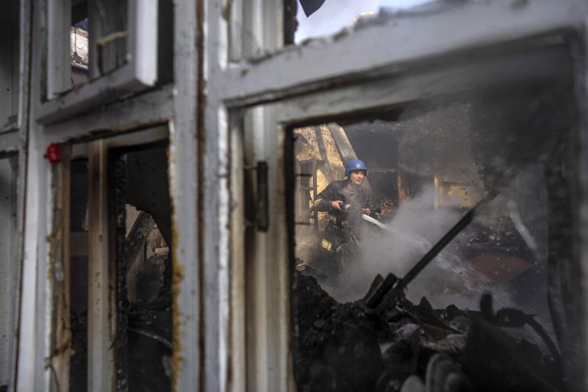 A Ukrainian firefighter tries to extinguish a fire inside a house destroyed by shelling in Kyiv, Ukraine, Wednesday, March 23, 2022. The Kyiv city administration says Russian forces shelled the Ukrainian capital overnight and early Wednesday morning, in the districts of Sviatoshynskyi and Shevchenkivskyi, damaging buildings. (AP Photo/Rodrigo Abd)
