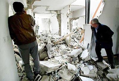 Azam Ahmad, right, Palestinian minister of public works, looks at the ruins of the building housing his offices and those of another ministry after the Israeli army left much of the West Bank city of Ramallah.