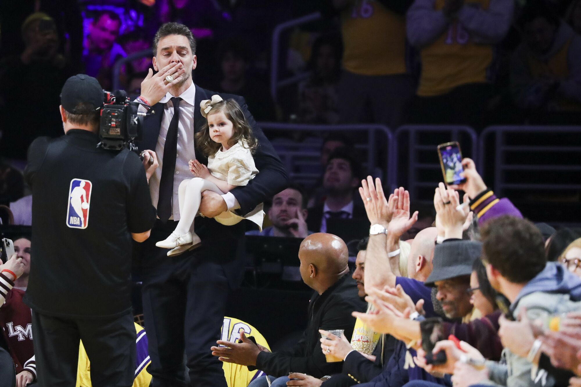 Pau Gasol blows a kiss to the fans while holding his daughter Elisabet Gianna Gasol as he makes his way onto the court.