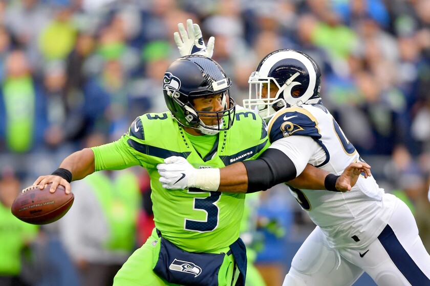 Seattle Seahawks quarterback Russell Wilson is pressured by Aaron Donald during the first half of the Seahawks' 30-29 win Thursday.