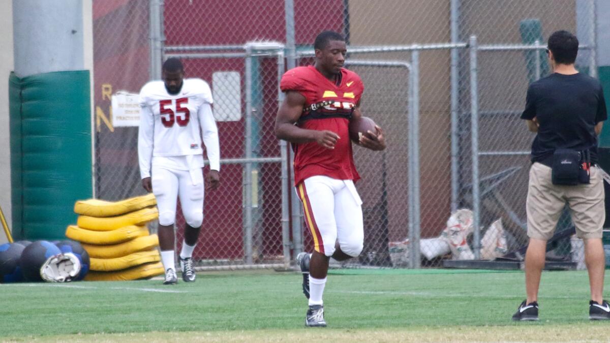 Running back Justin Davis (22) and linebacker Lamar Dawson (55) work with the USC training staff during practice at Howard Jones Field on Tuesday.