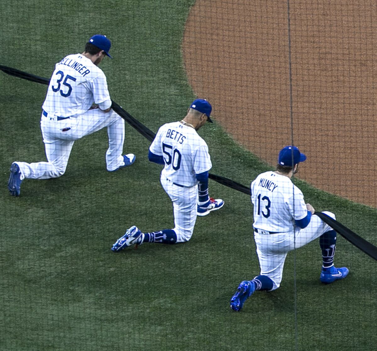 Dodgers Cody Bellinger, Mookie Betts and Max Muncy kneel.