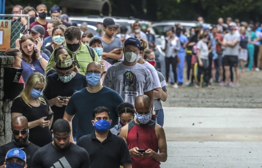 People in masks stand in a long line