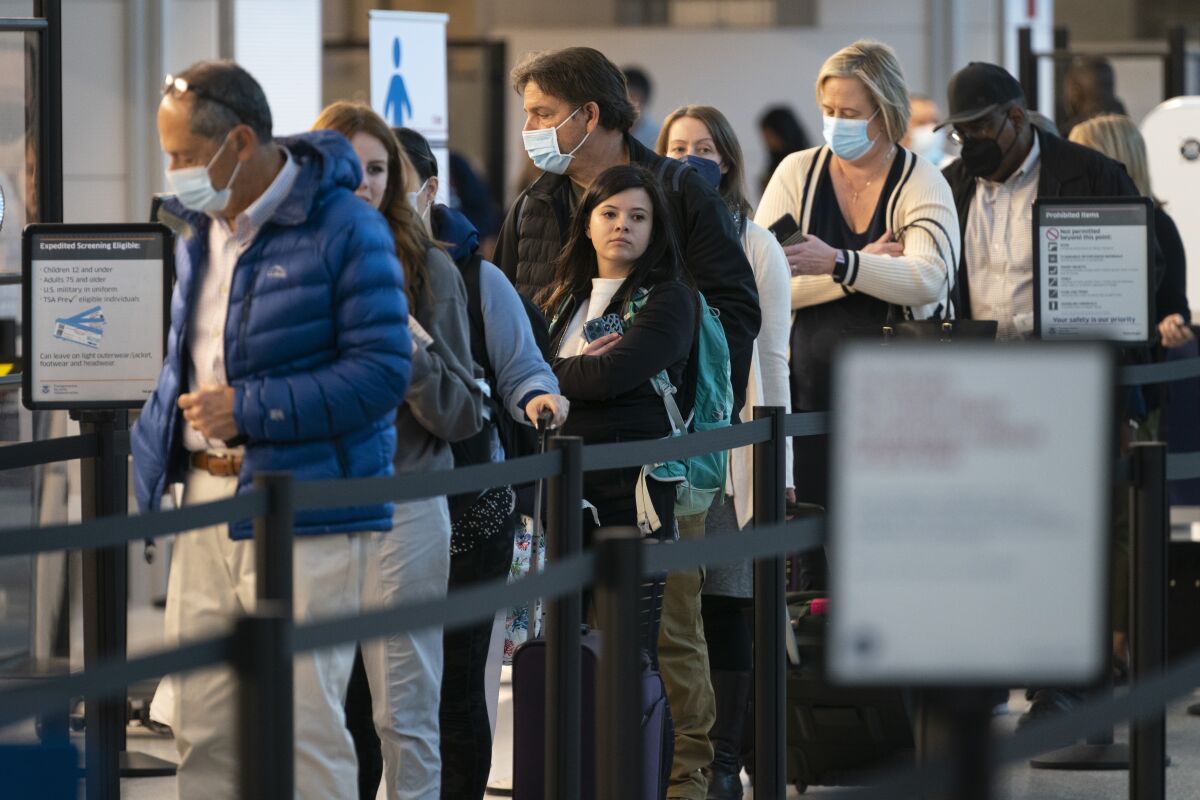 Passengers wait in line at the security checkpoint at Ronald Reagan Washington National Airport, in Arlington, Va.
