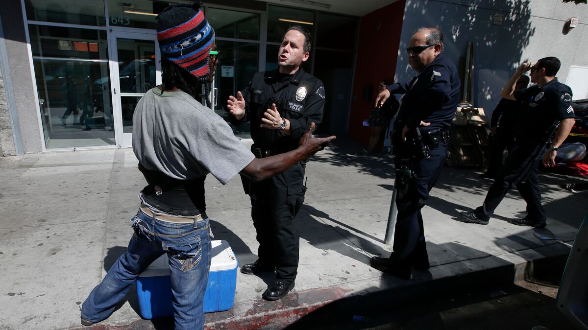 Los Angeles police officers talk to a homeless man on San Pedro Street along skid row.