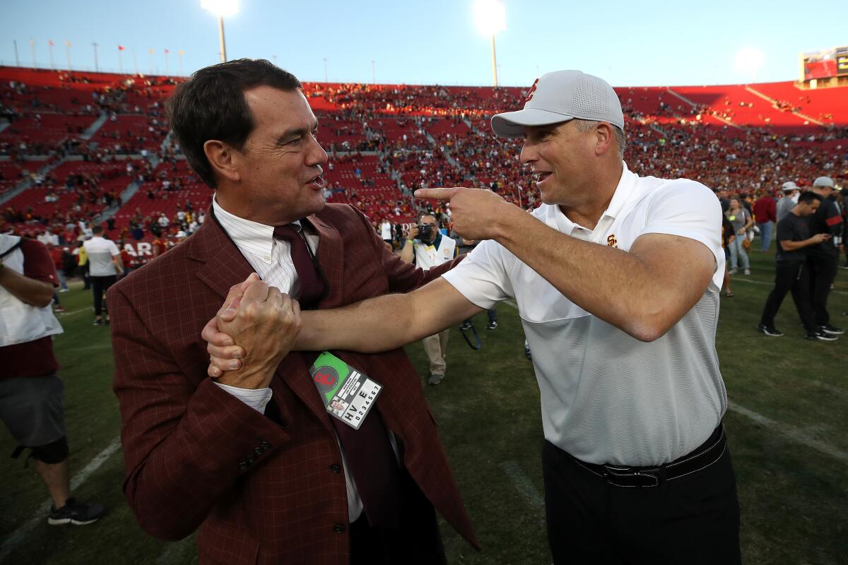 USC athletic director Mike Bohn, left, shakes hands with football coach Clay Helton after a win over UCLA on Nov. 23 at the Coliseum.