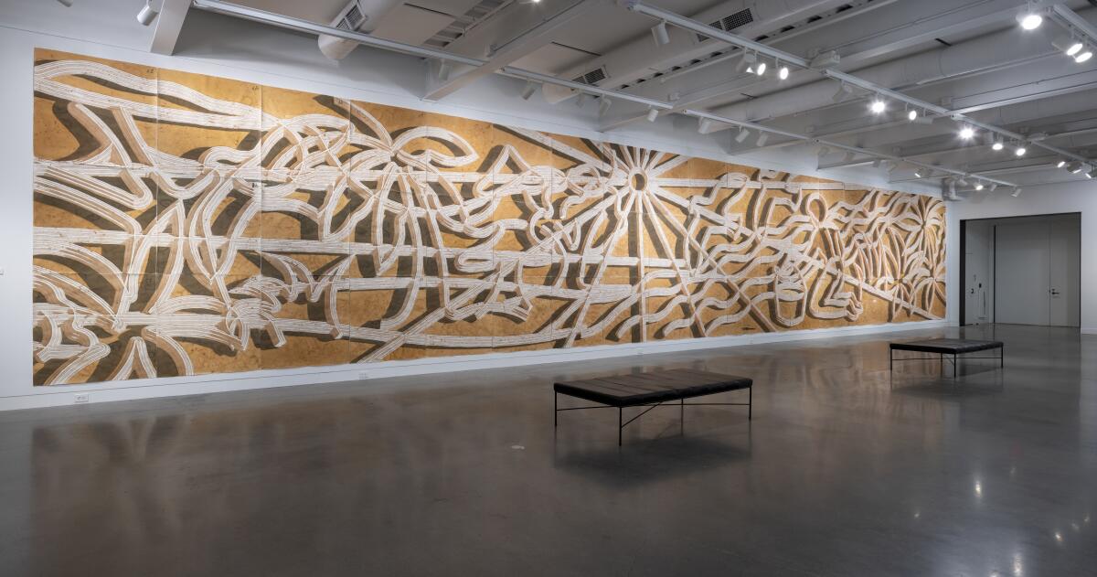 A large-scale mural of a landscape rendered with water and mud from a river occupies the entire wall of a gallery