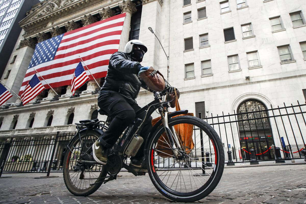 A delivery worker rides his electric bicycle past the New York Stock Exchange.