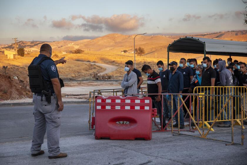 Palestinians laborers line up to cross a checkpoint at the entrance to the Israeli settlement of Maale Adumim, near Jerusalem, Tuesday, June 30, 2020. Israeli Prime Minister Benjamin Netanyahu appears determined to carry out his pledge to begin annexing parts of the occupied West Bank, possibly as soon as Wednesday. (AP Photo/Oded Balilty)