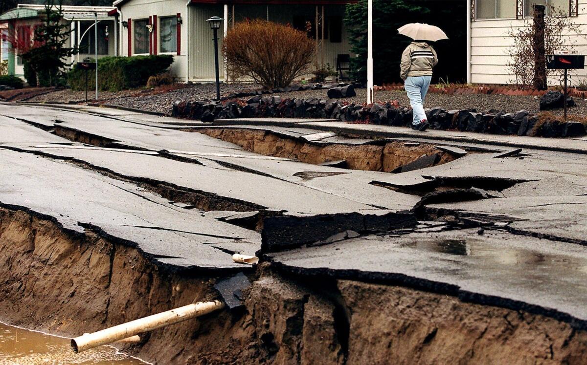 A pedestrian walks by a street damaged by an earthquake in Tumwater, Wash. in 2001. On Wednesday, several members of Congress sent a letter to President Obama, urging him to increase funding for an early earthquake warning program that they say would save lives and aid first responders and residents.
