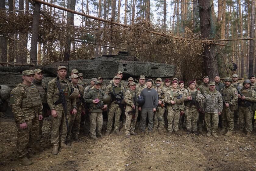 En esta imagen, distribuida por la oficina de prensa de la presidencia de Ucrania, el presidente, Volodymyr Zelenskyy (centro), posa para una foto con soldados delante de un tanque Leopard 2, en la línea del frente en al región de Járkiv, Ucrania, el 3 de octubre de 2023. (Oficina de Prensa de la Presidencia Ucraniana vía AP)