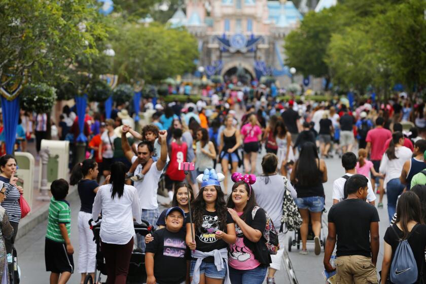 Visitors to Disneyland during its 60th Anniversary Diamond Jubilee use a selfie stick to take a photo on June 10, 2015.