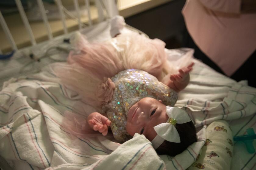 LOMA LINDA, CA - Septmber 7, 2020: Monica Ramirez, 38, of Corona dressed her newborn daughter Emiliana Ramirez in a new dress and a bow on her head inside the NICU at LomaLindaUniversityChildren's Hospital on Thursday, Aug. 27, 2020 in Loma Linda, CA. Monica was pregnant and became Covid positive. She gave birth to her daughter while in a coma at LomaLindaUniversityChildren's Hospital during the global coronavirus pandemic. This afternoon Emiliana is going home for the first time. (Francine Orr / Los Angeles Times)