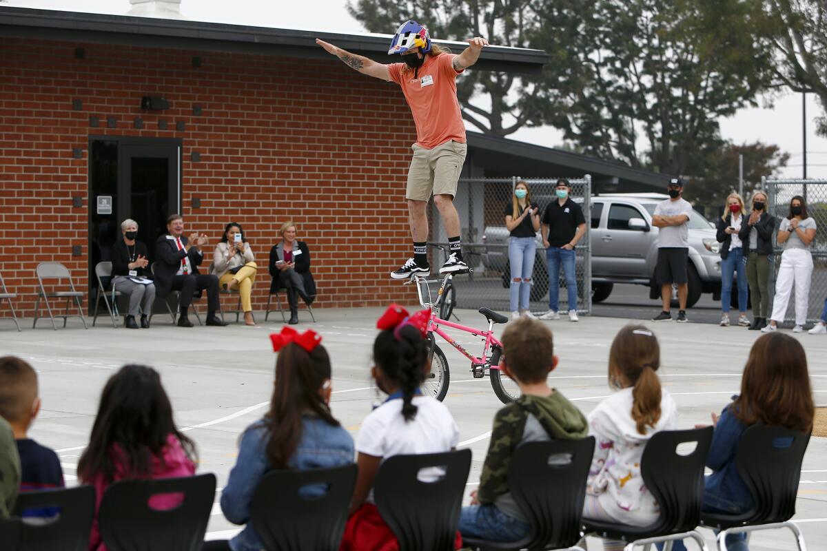 All Kids Bike ambassador Michael Clark stands on his handlebars as he performs for students at College View Elementary.