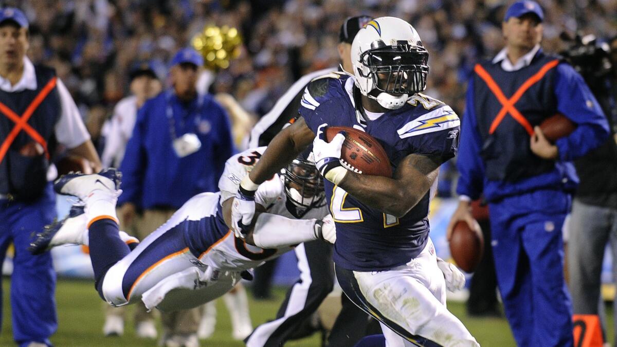 LaDainian Tomlinson breaks a tackle from Broncos' Vernon Fox to score a touchdown in 2008.