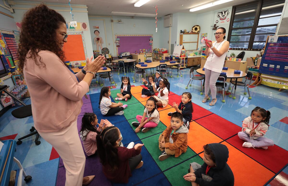 Transitional kindergarten students clap to songs with their teacher on the first day of school