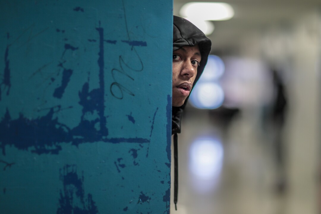 Flint's Dion Brown peers down a hallway as teammates gather before a bus takes them to a game against Davison High.