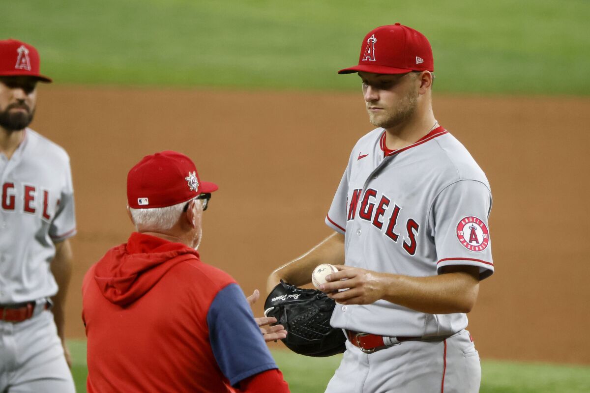 Los Angeles Angels starting pitcher Reid Detmers, right, gives the ball to manager Joe Maddon as he is pulled from a baseball game against the Texas Rangers during the fourth inning Friday, April 15, 2022, in Arlington, Texas. (AP Photo/Michael Ainsworth)